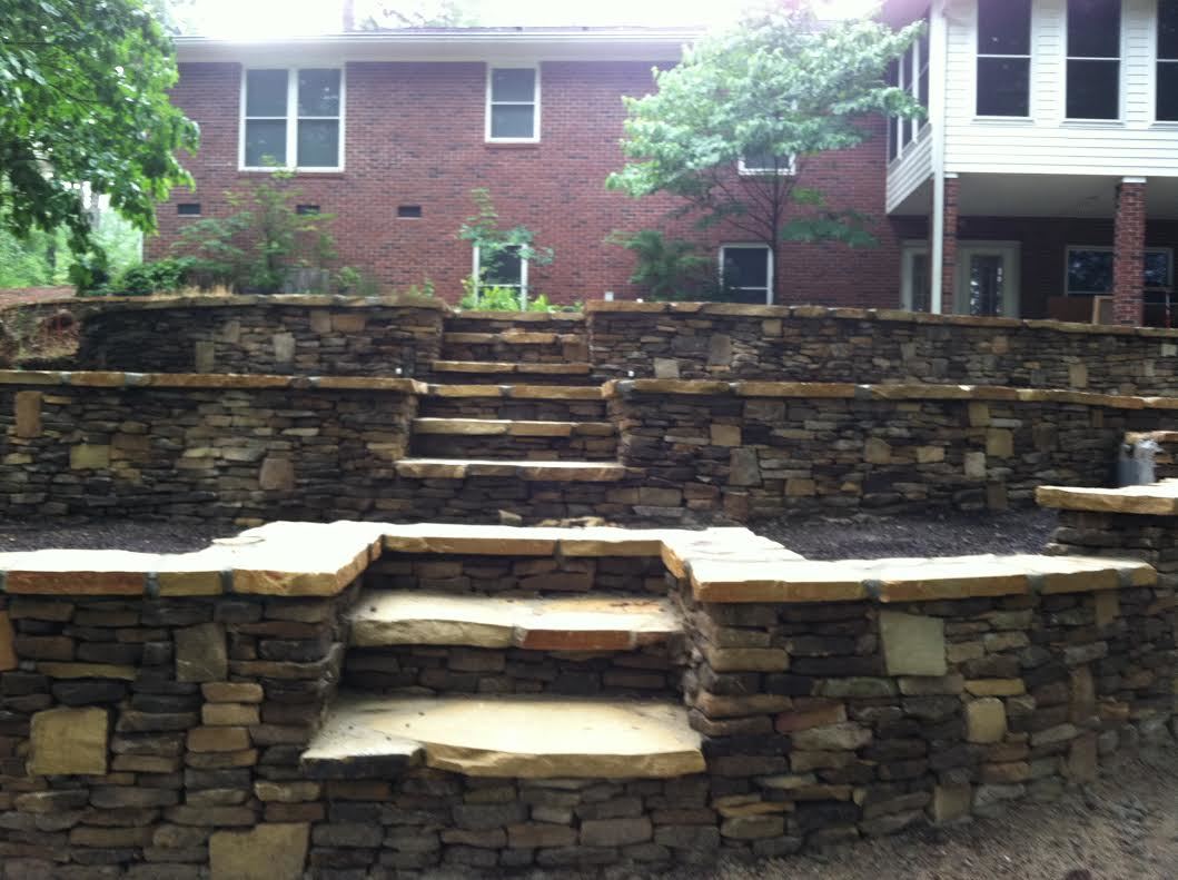 Stacked stone wall with dry leaves at the base.